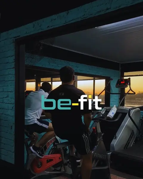 El cartel be-fit en neón sobre la pared turquesa, con bicis de spinning